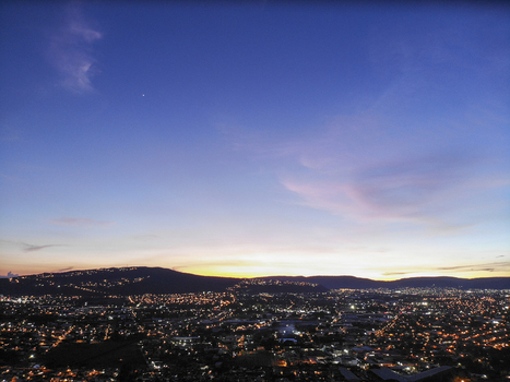 Aerial view of the city skyline illuminated by glowing lights at dusk with rolling hills in the background in Tlaquepaque Jalisco Mexico. Aerial view of the city skyline illuminated by glowing lights at dusk with rolling hills in the background in Tlaquepaque Jalisco Mexico.