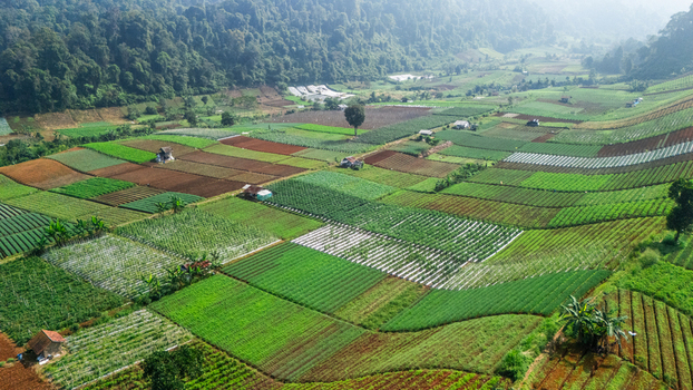 Aerial view of patchwork agricultural fields and terraced farms nestled against lush green forested hills in Sukabumi West Java Indonesia. Aerial view of patchwork agricultural fields and terraced farms nestled against lush green forested hills in Sukabumi West Java Indonesia.