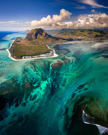 Aerial view of Le Morne Brabant mountain and the famous underwater waterfall illusion surrounded by turquoise coral reefs and white sand beaches Mauritius Moka District Mauritius. Aerial view of Le Morne Brabant mountain and the famous underwater waterfall illusion surrounded by turquoise coral reefs and white sand beaches Mauritius Moka District Mauritius.