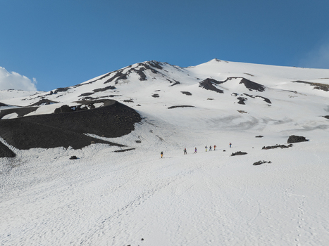 Aerial view of Mount Etna south side with hikers walking on the snow covered volcanic slopes under a clear blue sky in Nicolosi Sicily Italy. Aerial view of Mount Etna south side with hikers walking on the snow covered volcanic slopes under a clear blue sky in Nicolosi Sicily Italy.