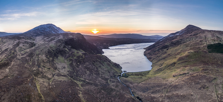 Aerial view of Altan Lough nestled among the rugged mountains during a vibrant sunset with rolling hills and a calm lake surface in County Donegal Ireland.