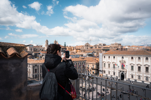 View of a woman capturing the timeless beauty of historic buildings and a bustling square from a high vantage point Taormina Sicily Italy. View of a woman capturing the timeless beauty of historic buildings and a bustling square from a high vantage point Taormina Sicily Italy.