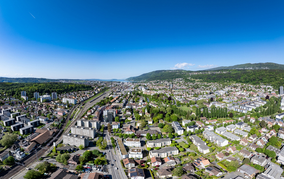 Aerial view of the urban landscape of Biel Bienne Bozingenfeld Champ featuring residential areas railway tracks and lush green trees under a clear blue sky in Biel Bienne Canton of Bern Switzerland.