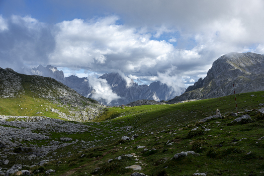 View of the rugged rocky terrain contrasts with the lush green meadows as clouds dance around the mountain peaks Picos de Europa Asturias Spain. View of the rugged rocky terrain contrasts with the lush green meadows as clouds dance around the mountain peaks Picos de Europa Asturias Spain.