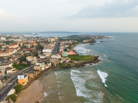Aerial view of the coastal city featuring historic architecture urban streets and waves crashing against the rocky shoreline Galle Southern Province Sri Lanka.