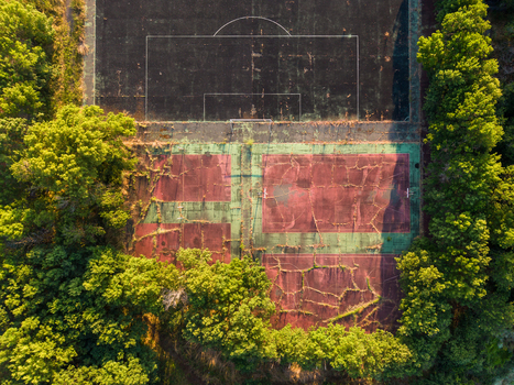 Aerial view of an abandoned sports court with cracked surfaces and overgrown vegetation surrounded by lush trees in Kiten Burgas Bulgaria. Aerial view of an abandoned sports court with cracked surfaces and overgrown vegetation surrounded by lush trees in Kiten Burgas Bulgaria.