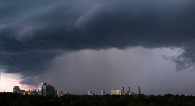 Aerial view of dramatic storm clouds and heavy rain over the city skyline and lush green trees Toronto Ontario Canada.
