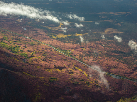Aerial view of Denali Highway winding through the tundra landscape with autumn colors scattered clouds and rugged terrain in Cantwell Alaska United States.