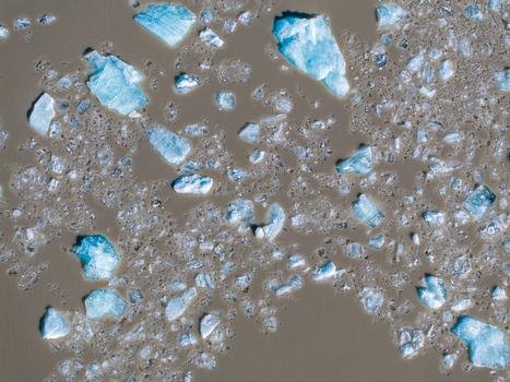 Aerial view of blue icebergs floating in the murky glacial waters of a lagoon in Iceland. Aerial view of blue icebergs floating in the murky glacial waters of a lagoon in Iceland.