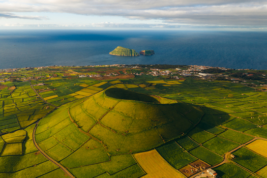 Aerial view of Pico Dona Joana geodesico volcanic cone surrounded by green patchwork fields and the Atlantic Ocean in Feteira Acores Portugal. Aerial view of Pico Dona Joana geodesico volcanic cone surrounded by green patchwork fields and the Atlantic Ocean in Feteira Acores Portugal.