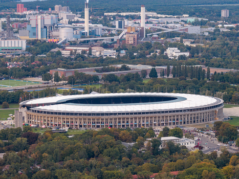 Aerial view of Olympiastadion Berlin surrounded by lush green trees and urban infrastructure in Berlin Berlin Germany.