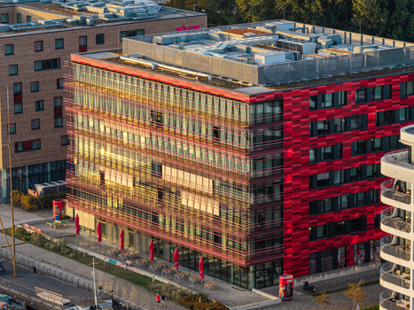 Aerial view of the Spreespeicher Promenade office building with its red facade and glass windows featuring an outdoor seating area in Berlin Berlin Germany. Aerial view of the Spreespeicher Promenade office building with its red facade and glass windows featuring an outdoor seating area in Berlin Berlin Germany.