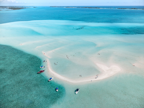 Aerial view of the Man O War Cay Sandbar with turquoise waters anchored boats and people enjoying the shallow sea in Rolletown Exuma The Bahamas. Aerial view of the Man O War Cay Sandbar with turquoise waters anchored boats and people enjoying the shallow sea in Rolletown Exuma The Bahamas.