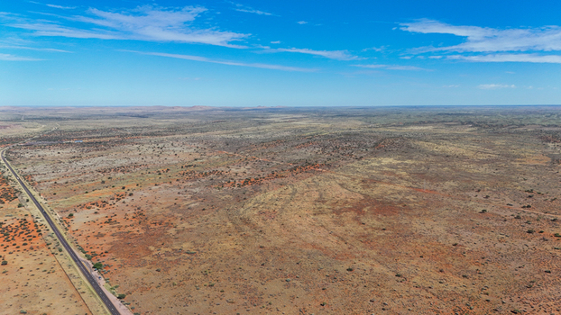 Aerial view of sun baked earth stretches to the horizon bisected by a lonely road under the vast blue sky Karoo Desert Northern Cape South Africa. Aerial view of sun baked earth stretches to the horizon bisected by a lonely road under the vast blue sky Karoo Desert Northern Cape South Africa.