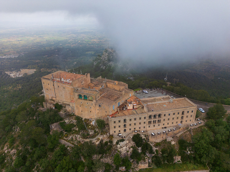 Aerial view of the Sanctuary of Sant Salvador on a rocky hilltop surrounded by lush green forests and low clouds Felanitx Illes Balears Spain. Aerial view of the Sanctuary of Sant Salvador on a rocky hilltop surrounded by lush green forests and low clouds Felanitx Illes Balears Spain.