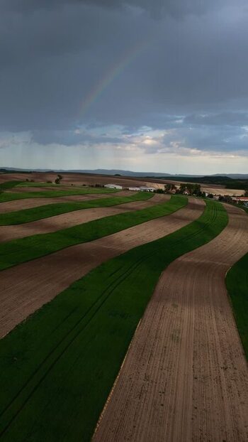 Aerial view of striped fields and a rainbow in Czechia.