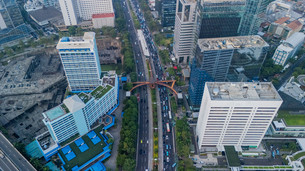 Aerial view of the dense urban landscape featuring modern skyscrapers busy multi lane traffic on the highway and surrounding commercial buildings in Jakarta Indonesia.