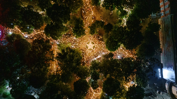 Aerial view of a crowded park at night illuminated by numerous glowing lights and lanterns with people gathered among dense trees in Sremska Mitrovica Serbia. Aerial view of a crowded park at night illuminated by numerous glowing lights and lanterns with people gathered among dense trees in Sremska Mitrovica Serbia.