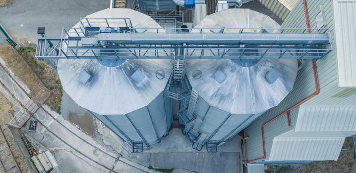 Aerial view of grain silos connected by an overhead conveyor system showcasing industrial geometry and modern agricultural storage infrastructure in Le Pouzin Auvergne Rhone Alpes France.