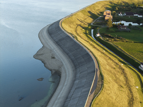 Aerial view of Lake Czorsztynskie dam featuring concrete embankment grassy slopes and calm water under golden hour light in Nowy Targ Lesser Poland Voivode Poland.