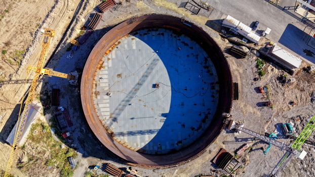 Aerial view of the assembly of a large circular oil storage tank at an industrial construction site with cranes and building materials in Kovin Vojvodina Serbia. Aerial view of the assembly of a large circular oil storage tank at an industrial construction site with cranes and building materials in Kovin Vojvodina Serbia.