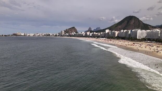 Aerial view of Copacabana Beach with waves and mountains Brazil.