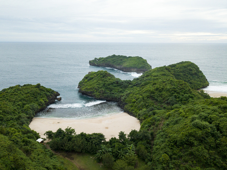 Aerial view of the secluded beach nestled between lush green hills and the vast ocean a hidden paradise Sedahan Beach Gunungkidul Regency Special Region of Yogyakarta Indonesia. Aerial view of the secluded beach nestled between lush green hills and the vast ocean a hidden paradise Sedahan Beach Gunungkidul Regency Special Region of Yogyakarta Indonesia.