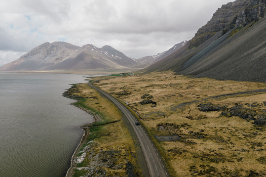 Aerial view of the coastal road near Stokksnes with dramatic mountains rugged grassy terrain and the sea in Iceland.