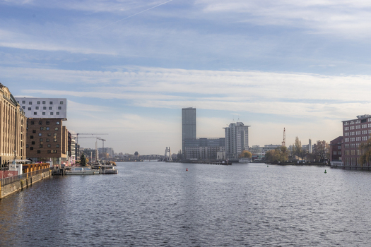 View of the Spree river flanked by modern architecture and historic brick buildings under a clear sky with the Treptowers skyscraper in Berlin Berlin Germany. View of the Spree river flanked by modern architecture and historic brick buildings under a clear sky with the Treptowers skyscraper in Berlin Berlin Germany.