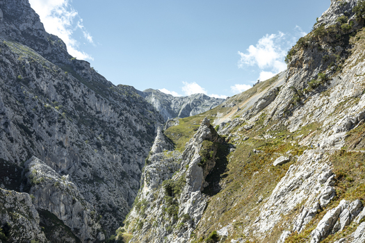 View of a dramatic gorge carved through jagged mountains where rugged cliffs meet the sky in Picos de Europa Asturias Spain. View of a dramatic gorge carved through jagged mountains where rugged cliffs meet the sky in Picos de Europa Asturias Spain.