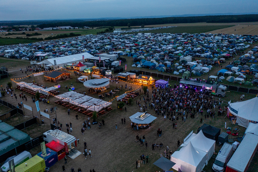 Herzogenaurach Germany 25 July 2025 Aerial view of Open Beatz Festival featuring a large campsite with colorful tents food stalls and crowds of people at dusk. Herzogenaurach Germany 25 July 2025 Aerial view of Open Beatz Festival featuring a large campsite with colorful tents food stalls and crowds of people at dusk.