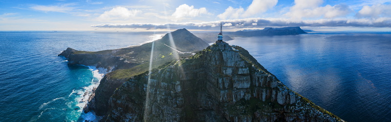Aerial view of the Cape of Good Hope featuring the iconic lighthouse tower on a rugged cliff overlooking the vast blue ocean in Cape Town Western Cape South Africa.
