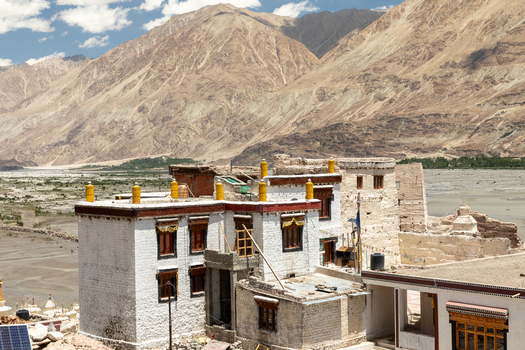 View of the historic Charasa Gonpa monastery with its white washed walls and yellow finials set against a backdrop of rugged mountains in Charasa Ladakh India.