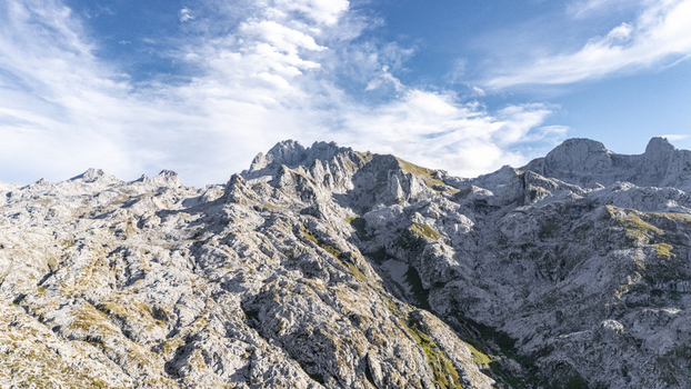 Aerial view of jagged rocky peaks under a serene sky the rough stone contrasting with the soft clouds Picos de Europa Asturias Spain.