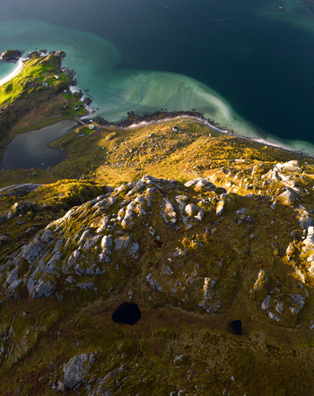 Aerial view of the rugged coastline of Tangstad featuring turquoise waters sandy beaches and rocky mountain peaks under warm golden sunlight in Leknes Nordland Norway. Aerial view of the rugged coastline of Tangstad featuring turquoise waters sandy beaches and rocky mountain peaks under warm golden sunlight in Leknes Nordland Norway.