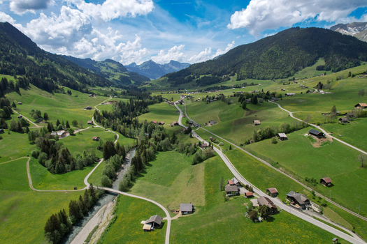Aerial view of the village of Rougemont nestled in a lush green valley with traditional chalets a winding river and forested mountains Rougemont Vaud Switzerland. Aerial view of the village of Rougemont nestled in a lush green valley with traditional chalets a winding river and forested mountains Rougemont Vaud Switzerland.