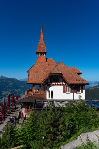 View of the Harder Kulm restaurant with its distinctive red tiled roof and tower set against a clear blue sky with mountain views in Unterseen Canton of Bern Switzerland.