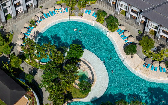 Aerial view of the swimming pool at Marriott s Bali Nusa Dua Gardens surrounded by lush palm trees and sun loungers in Kecamatan Kuta Selatan Bali Indonesia.