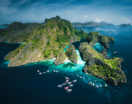 Aerial view of Big Lagoon featuring dramatic limestone cliffs vibrant turquoise waters and traditional outrigger boats anchored in El Nido Philippines. Aerial view of Big Lagoon featuring dramatic limestone cliffs vibrant turquoise waters and traditional outrigger boats anchored in El Nido Philippines.