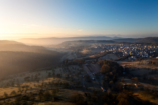 Aerial view of the village of Hagelloch nestled among rolling hills and misty valleys during a golden sunrise in Tubingen Baden Wurttemberg Germany.