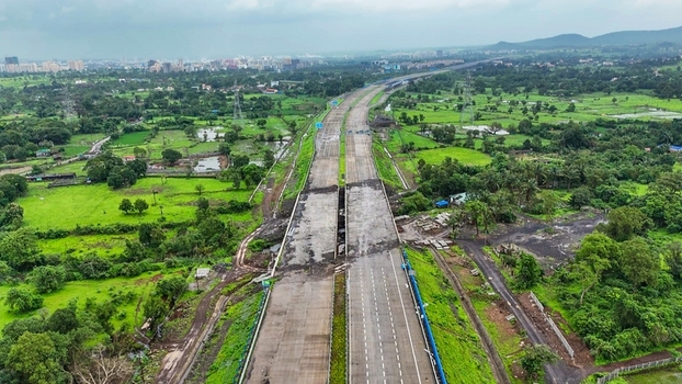 Aerial view of the Delhi Mumbai Expressway cutting through lush green landscapes and rural fields near Badlapur Maharashtra India. Aerial view of the Delhi Mumbai Expressway cutting through lush green landscapes and rural fields near Badlapur Maharashtra India.