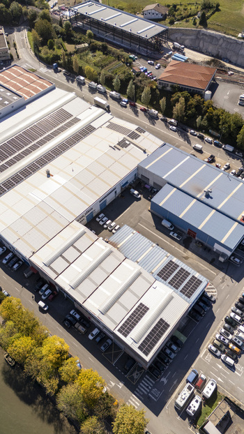 Aerial view of industrial buildings with solar panels on the rooftops parking lots and surrounding road infrastructure in Zumaia Basque Country Spain.