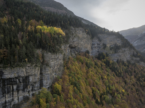 Aerial view of the Pyrenees mountain range featuring steep rocky cliffs and dense forests with vibrant autumn foliage in Spain. Aerial view of the Pyrenees mountain range featuring steep rocky cliffs and dense forests with vibrant autumn foliage in Spain.