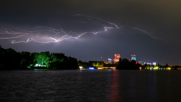 View of a powerful lightning bolt illuminating the night sky over the city skyline and lake in Bucharest Bucharest Romania. View of a powerful lightning bolt illuminating the night sky over the city skyline and lake in Bucharest Bucharest Romania.