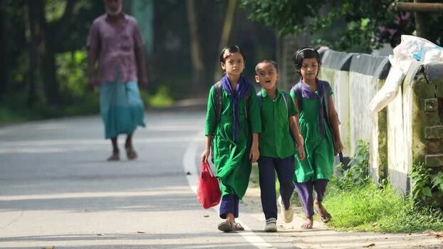 View of school children walking on a rural road in Bogura Bangladesh.