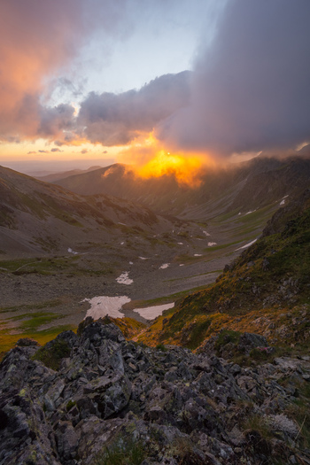 View of Smutne sedlo in Western Tatras with golden sunset light breaking through clouds over a rocky mountain valley in Ziar Zilina Region Slovakia. View of Smutne sedlo in Western Tatras with golden sunset light breaking through clouds over a rocky mountain valley in Ziar Zilina Region Slovakia.