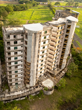 Aerial view of the abandoned Sonesta One Resort building with concrete walls and graffiti surrounded by green fields in Jaco Provincia de Puntarenas Costa Rica. Aerial view of the abandoned Sonesta One Resort building with concrete walls and graffiti surrounded by green fields in Jaco Provincia de Puntarenas Costa Rica.