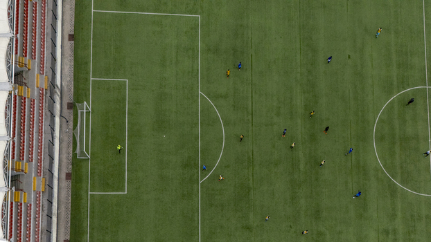 Aerial view of a soccer match in progress on a green pitch with players in colorful jerseys and stadium seating visible in Lagos Lagos Nigeria. Aerial view of a soccer match in progress on a green pitch with players in colorful jerseys and stadium seating visible in Lagos Lagos Nigeria.