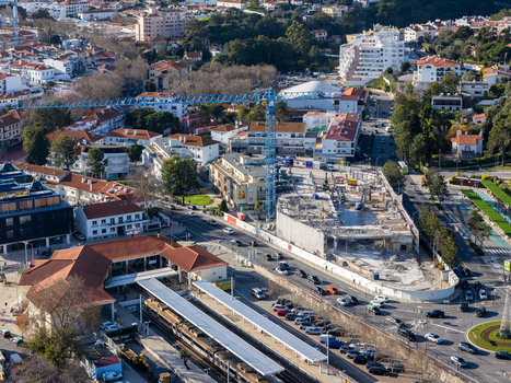 Aerial view of a construction site with a towering crane casting shadows over the train station and roundabout Cascais Lisbon Portugal.