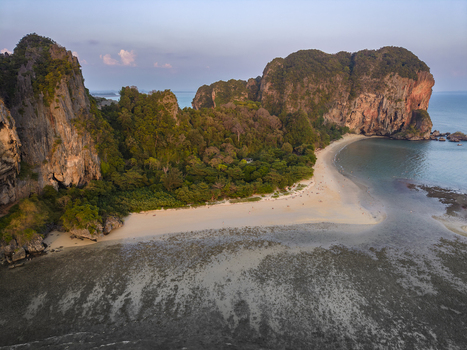 Aerial view of the dramatic coastline meeting the turquoise sea with golden cliffs embracing the lush greenery Krabi Thailand.